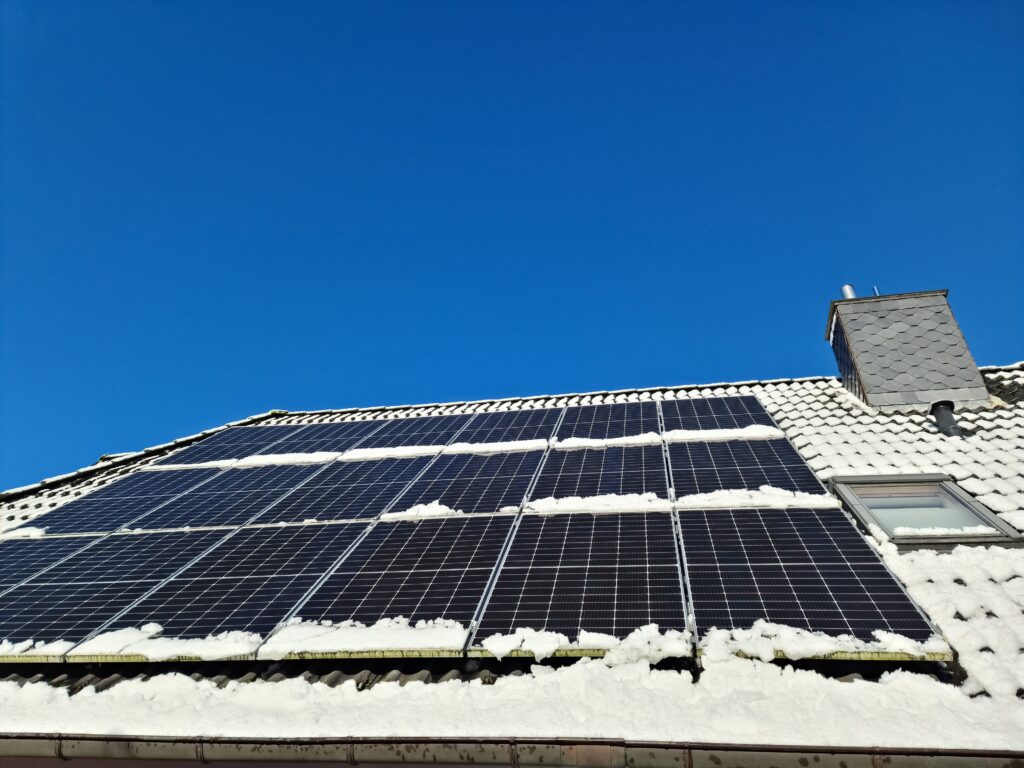 View of a roof with many solar cells in winter with some snow on the roof.